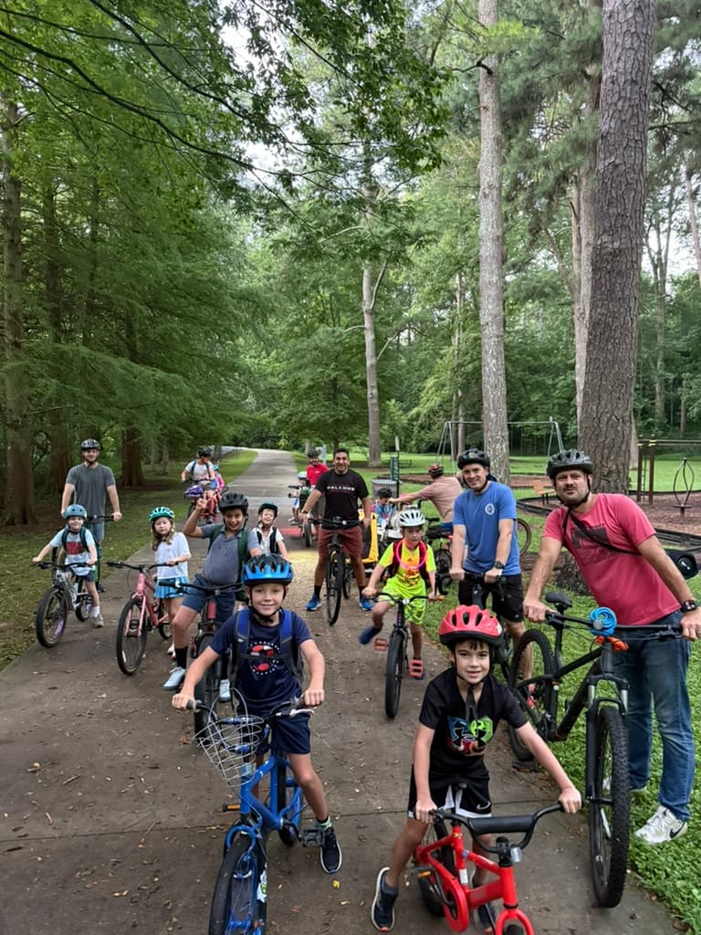 Kids and dads on bikes lined up on the tree-lined path, ready to roll